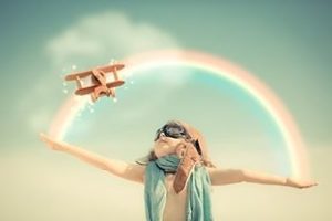 child below rainbow with toy airplane